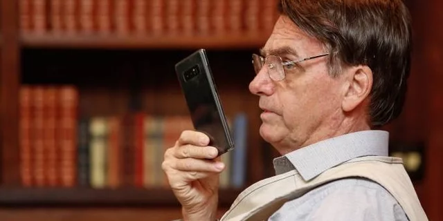 Bolsonaro holding a cell phone with his right hand in front of his face