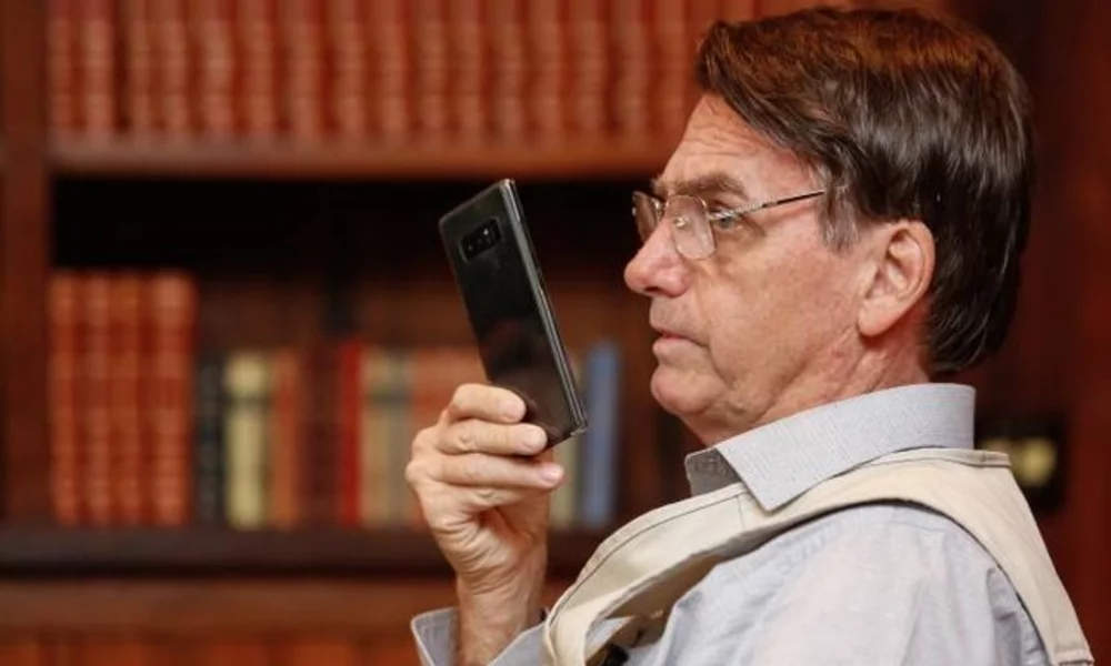 Bolsonaro holding a cell phone with his right hand in front of his face